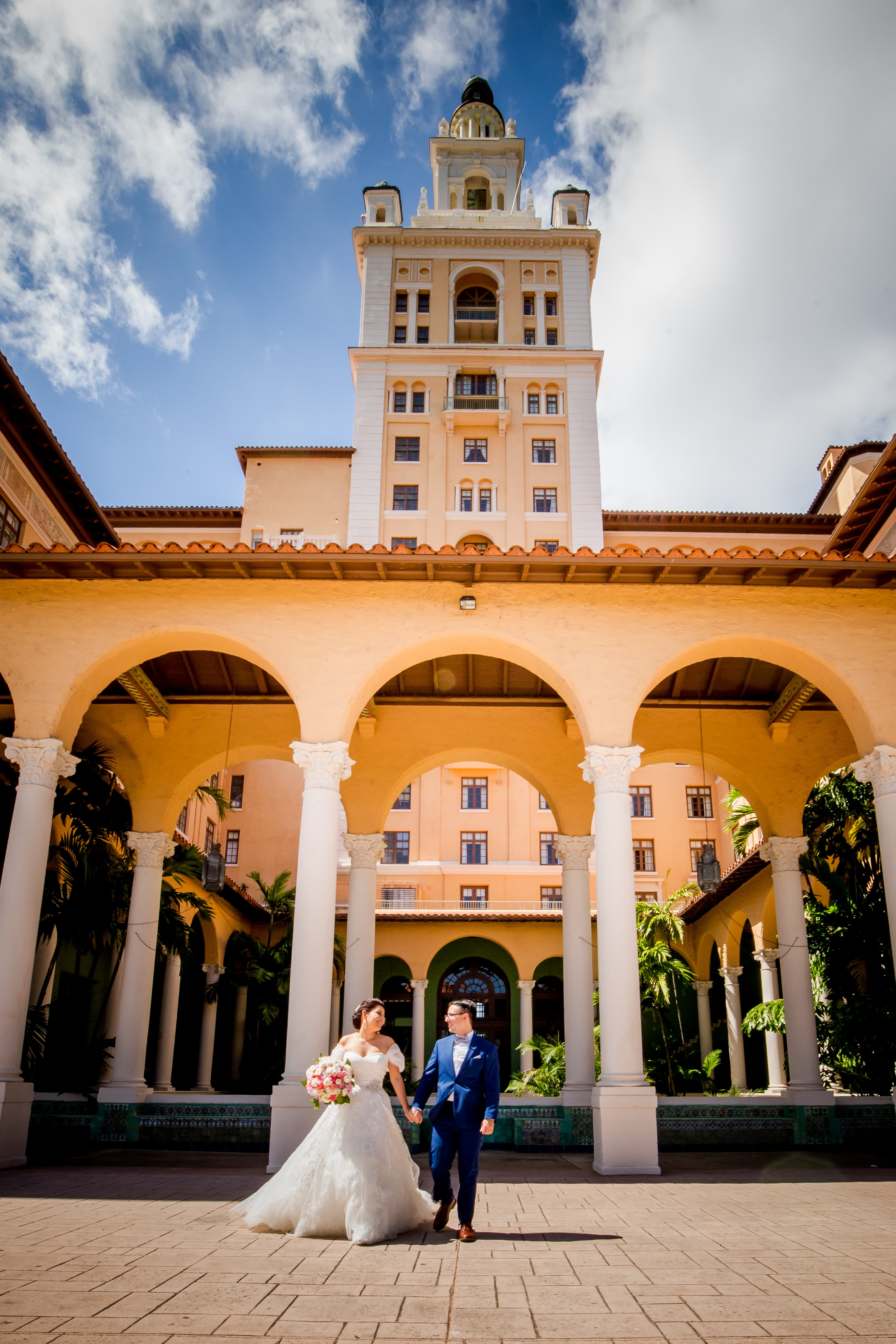 Couple walking the arched colonnade courtyard beneath the Biltmore tower — The Biltmore Hotel