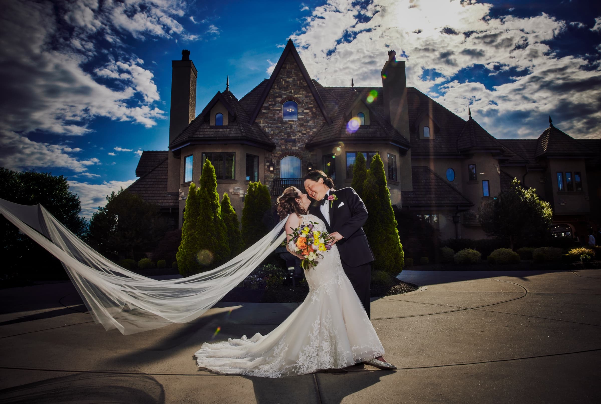 Veil sweeping in the wind as the couple kiss in front of the manor — Champagne Manor wedding venue, Monroe, North Carolina