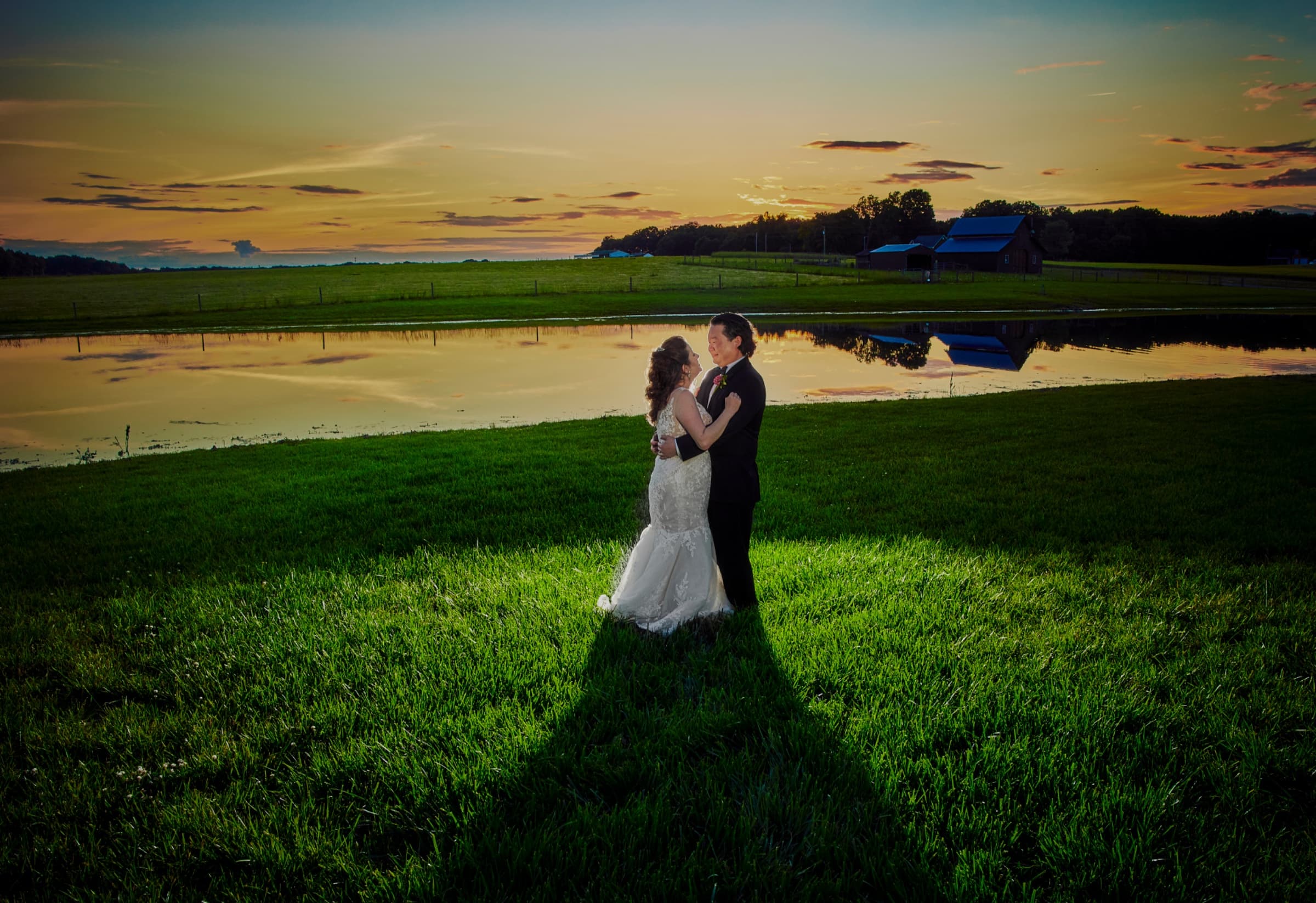 Sunset portrait beside the pond, the sky mirrored in the water with the barn beyond — Champagne Manor
