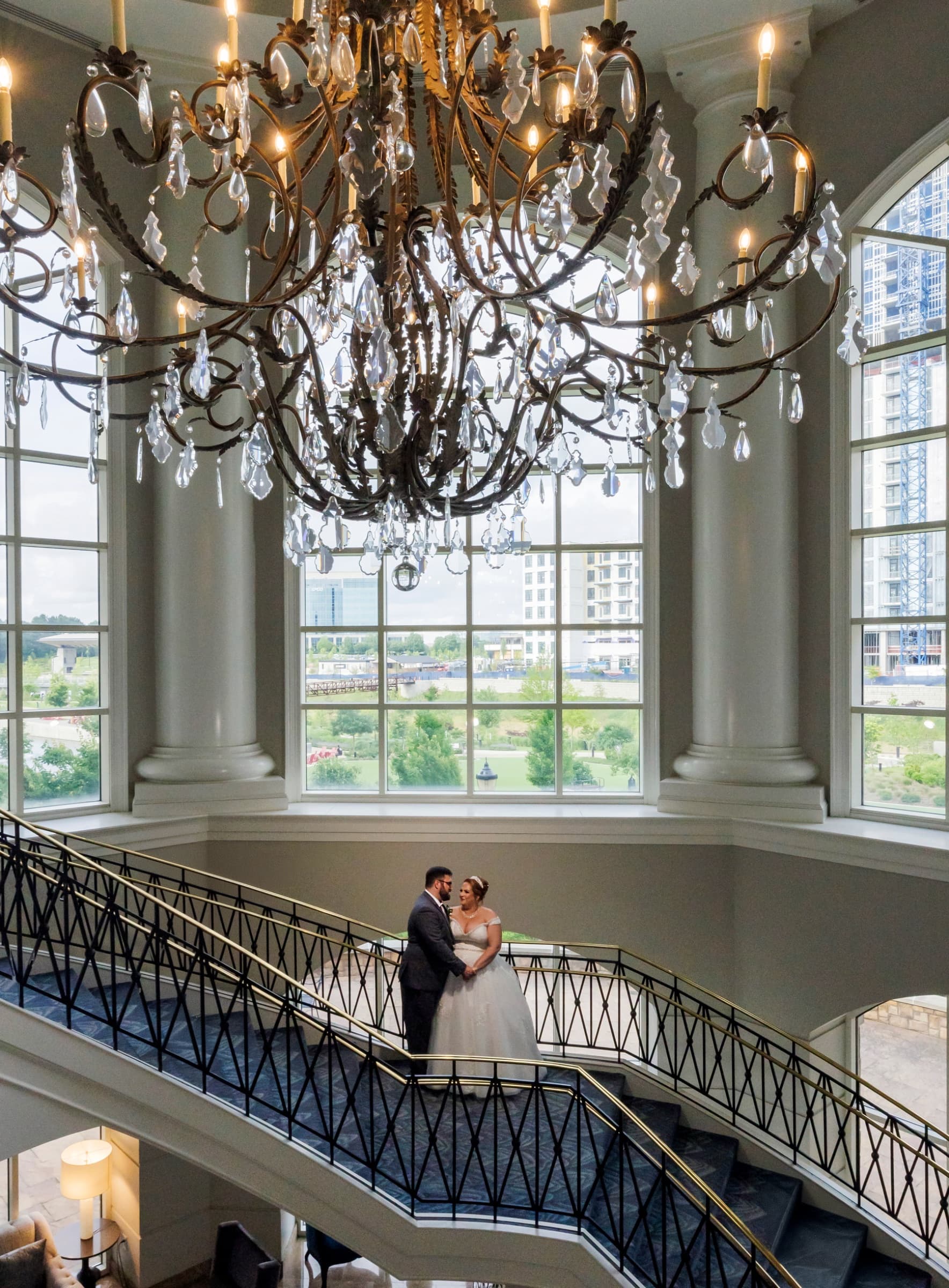 Couple on the sweeping staircase beneath the crystal chandelier — The Ballantyne Hotel