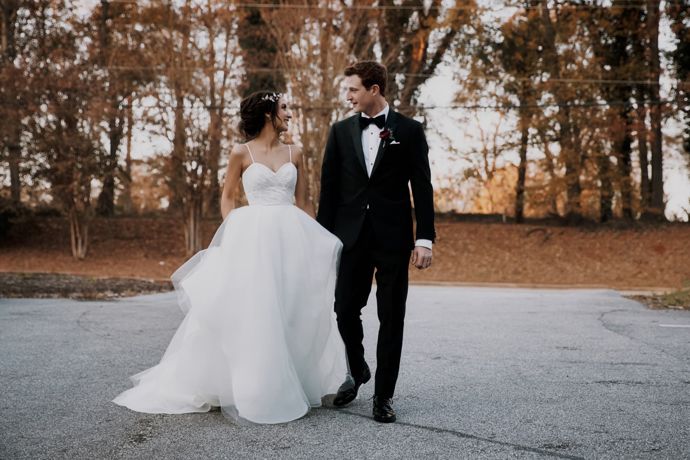Couple walking at golden hour with autumn woodland behind — The Rutherford wedding venue, Greenville, South Carolina