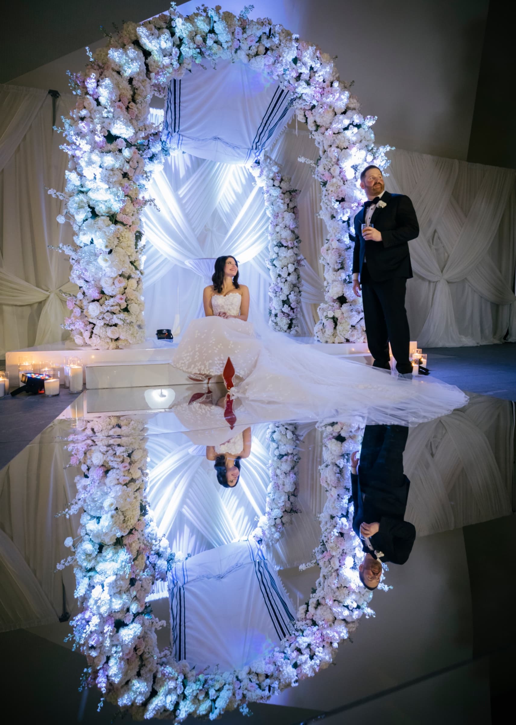 Sweetheart table inside a floral arch, mirrored floor doubling the blooms — The Ritz-Carlton Charlotte