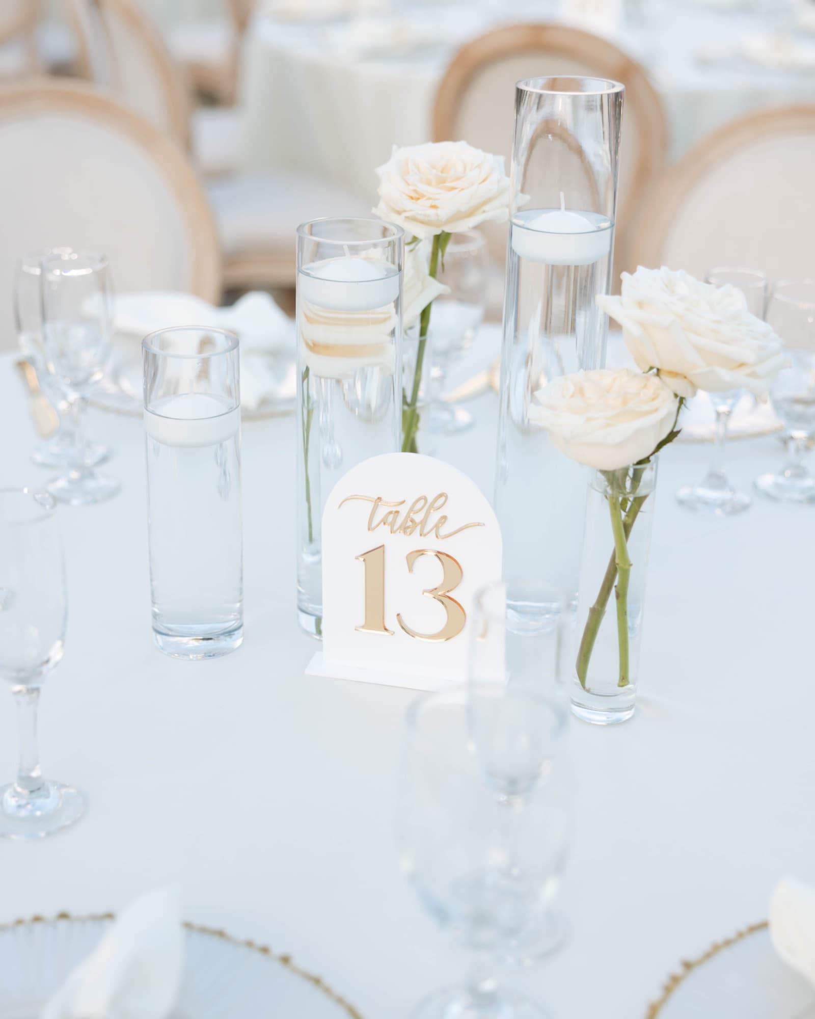 Table thirteen set with white roses and gold-rimmed glassware — The Glass Venue wedding venue, Miami, Florida