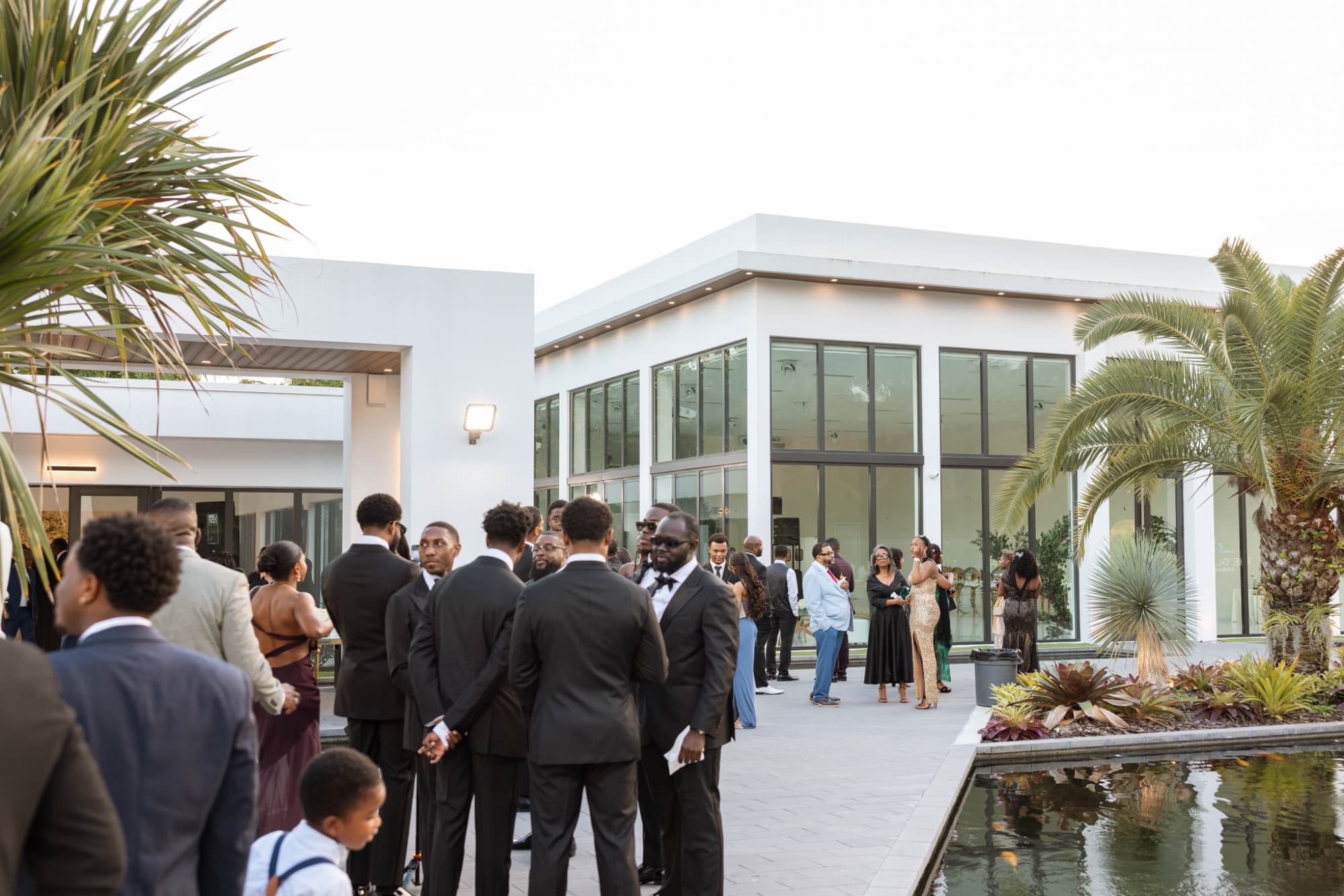 Guests outside the glass reception building by the reflecting pool — The Glass Venue wedding venue, Miami, Florida