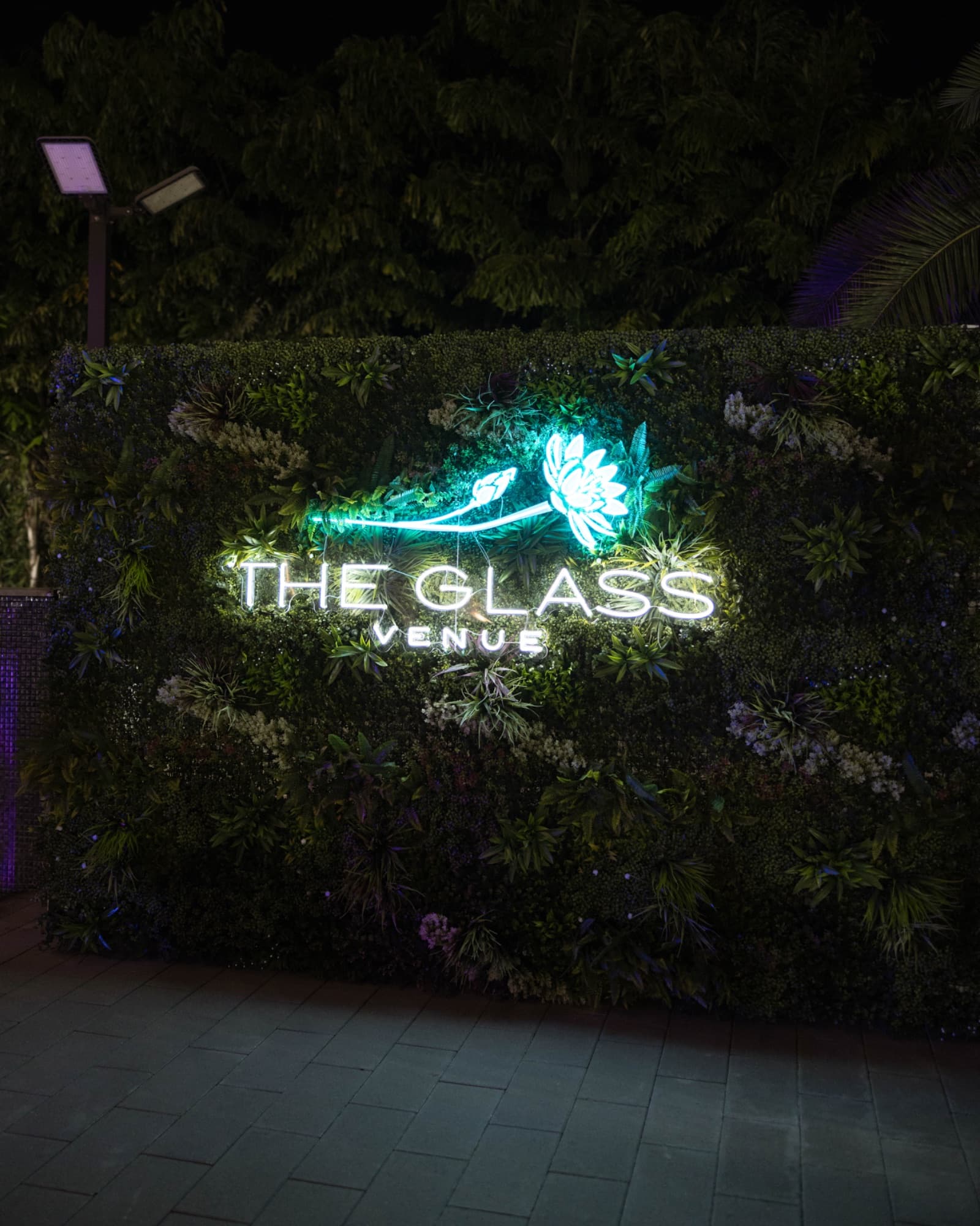 The Glass Venue's sign lit against the hedge wall at night — The Glass Venue wedding venue, Miami, Florida