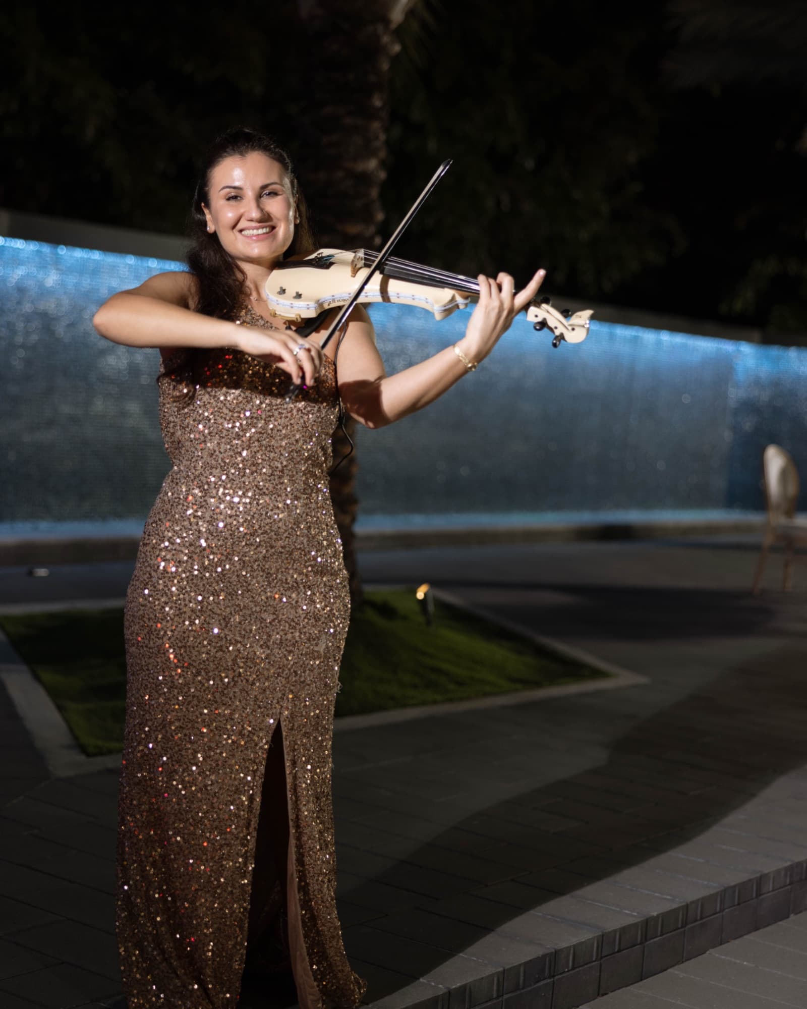 A violinist playing beside the illuminated waterfall — The Glass Venue wedding venue, Miami, Florida